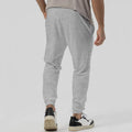 Man wearing grey tapered straight-leg casual sweatpants with a mid-rise elastic waistband.