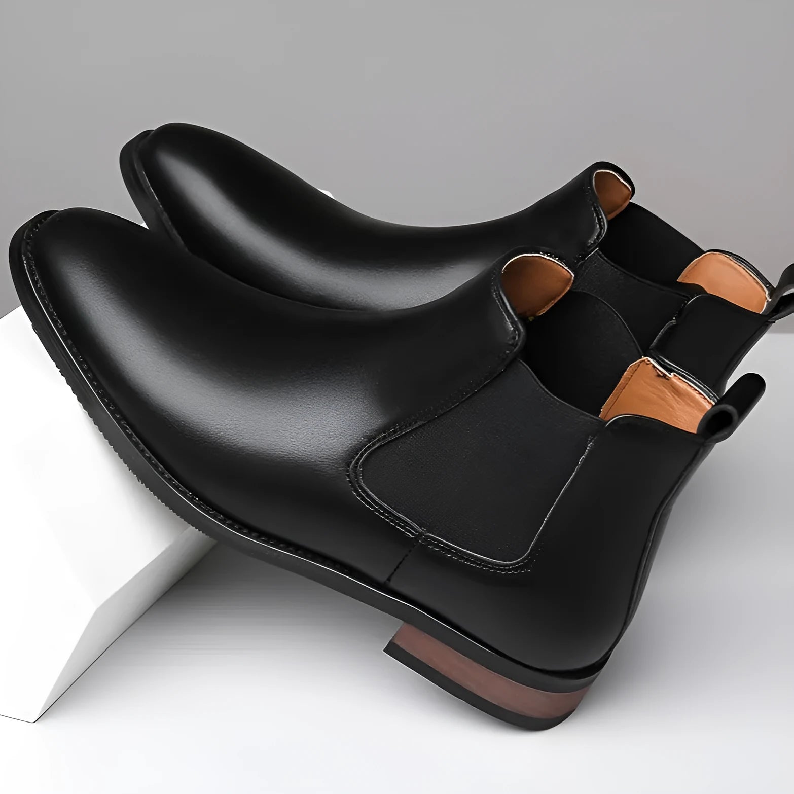 Men's black pointed-toe Chelsea boots with a low heel and rubber sole on a white background.