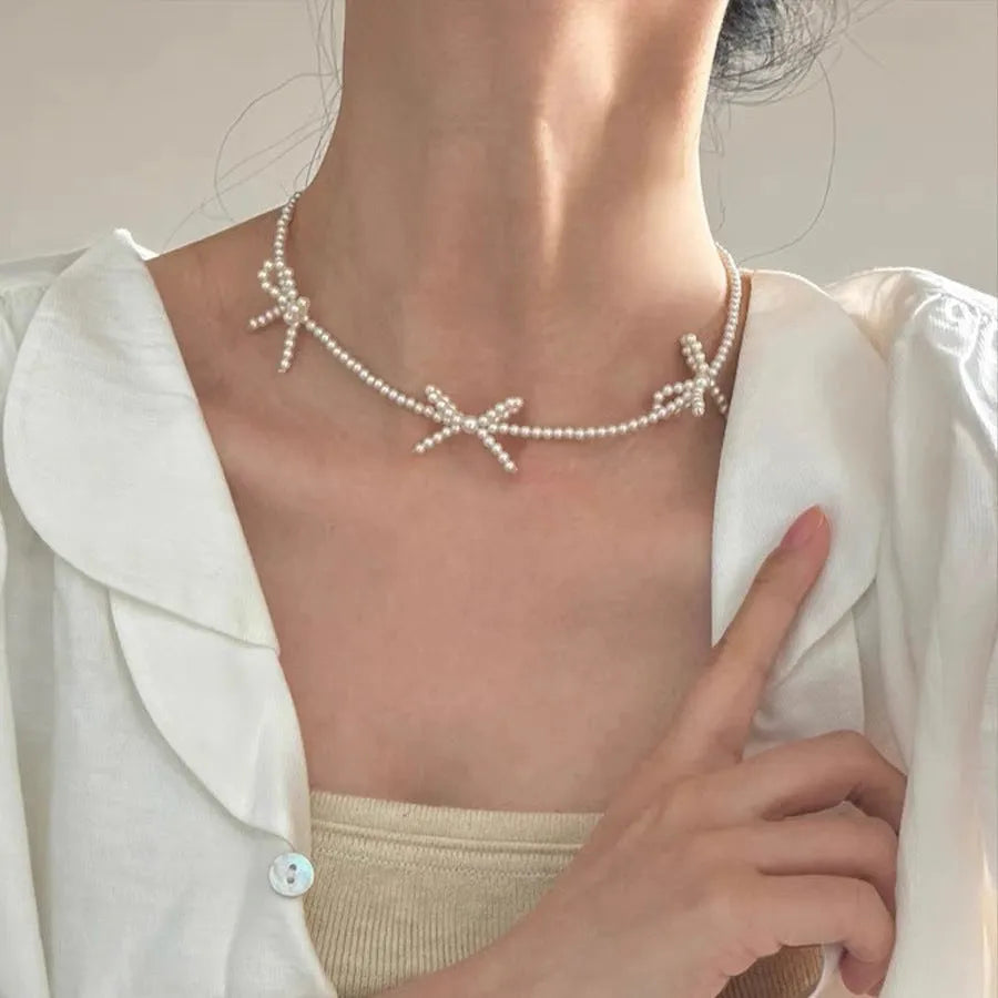White bow pearl necklace with geometric clasp on woman at clavicle length