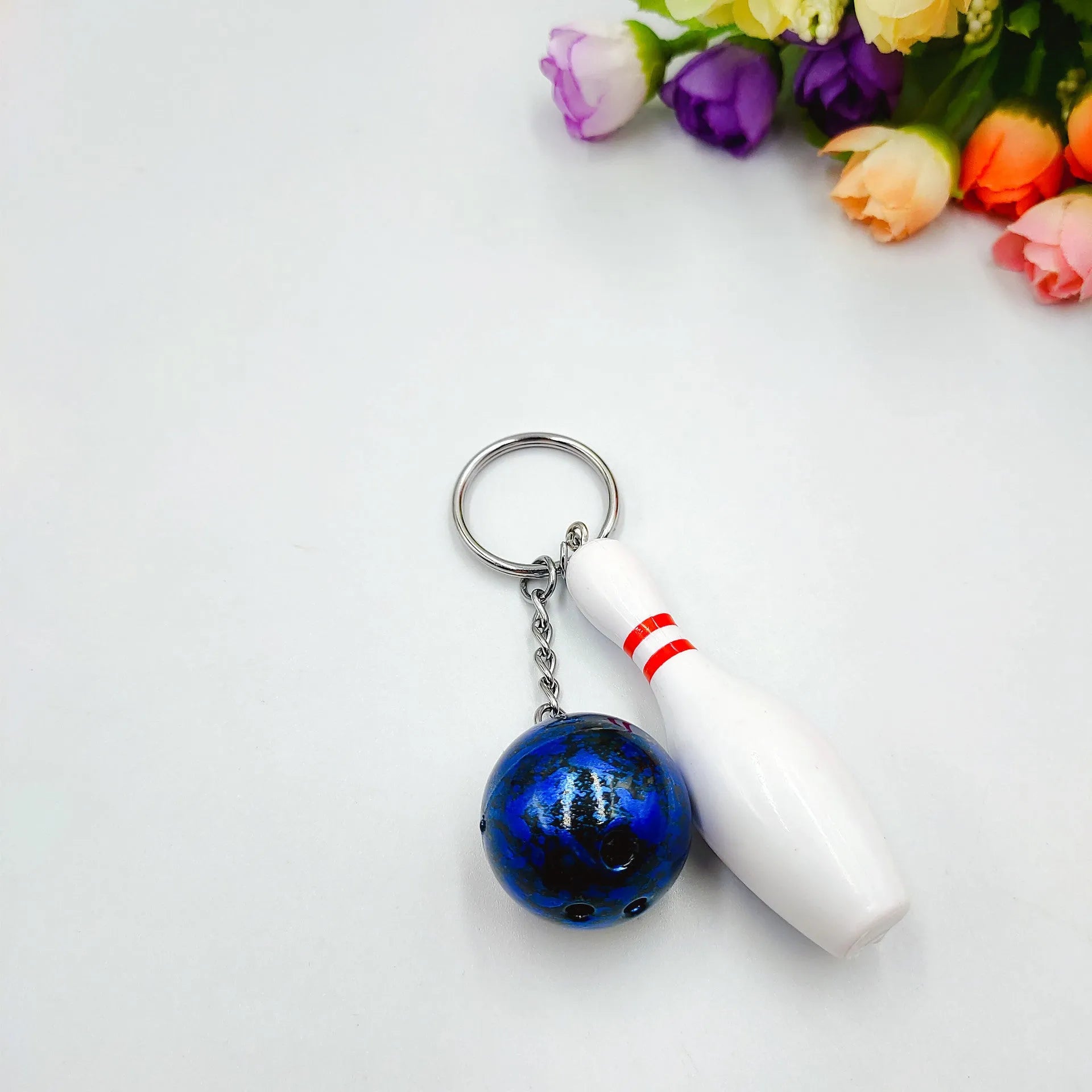 Mini bowling ball keychain pendant in PVC metal showing four colour options: dark red, blue, purple, green
