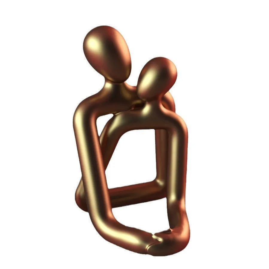 Modern loving couple resin statue in milky white or gold colour on a desk.