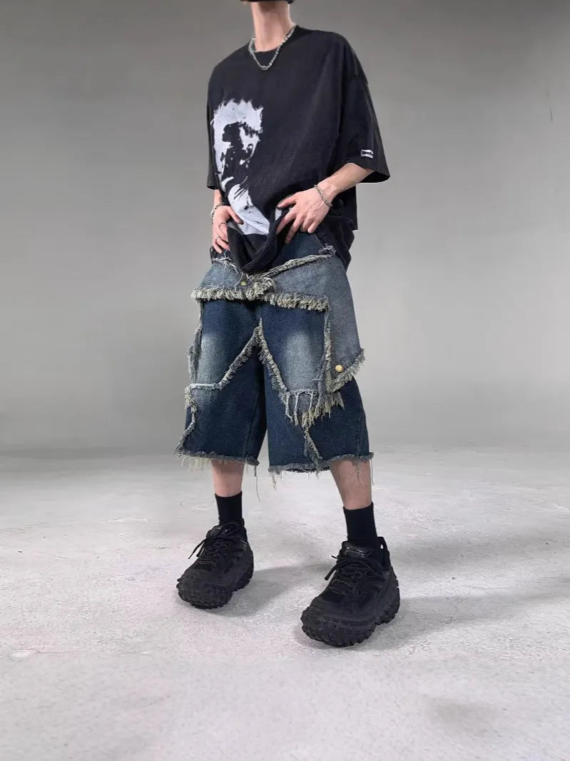 Man wearing blue loose-fit denim shorts with frayed five-pointed star embroidery on the leg.